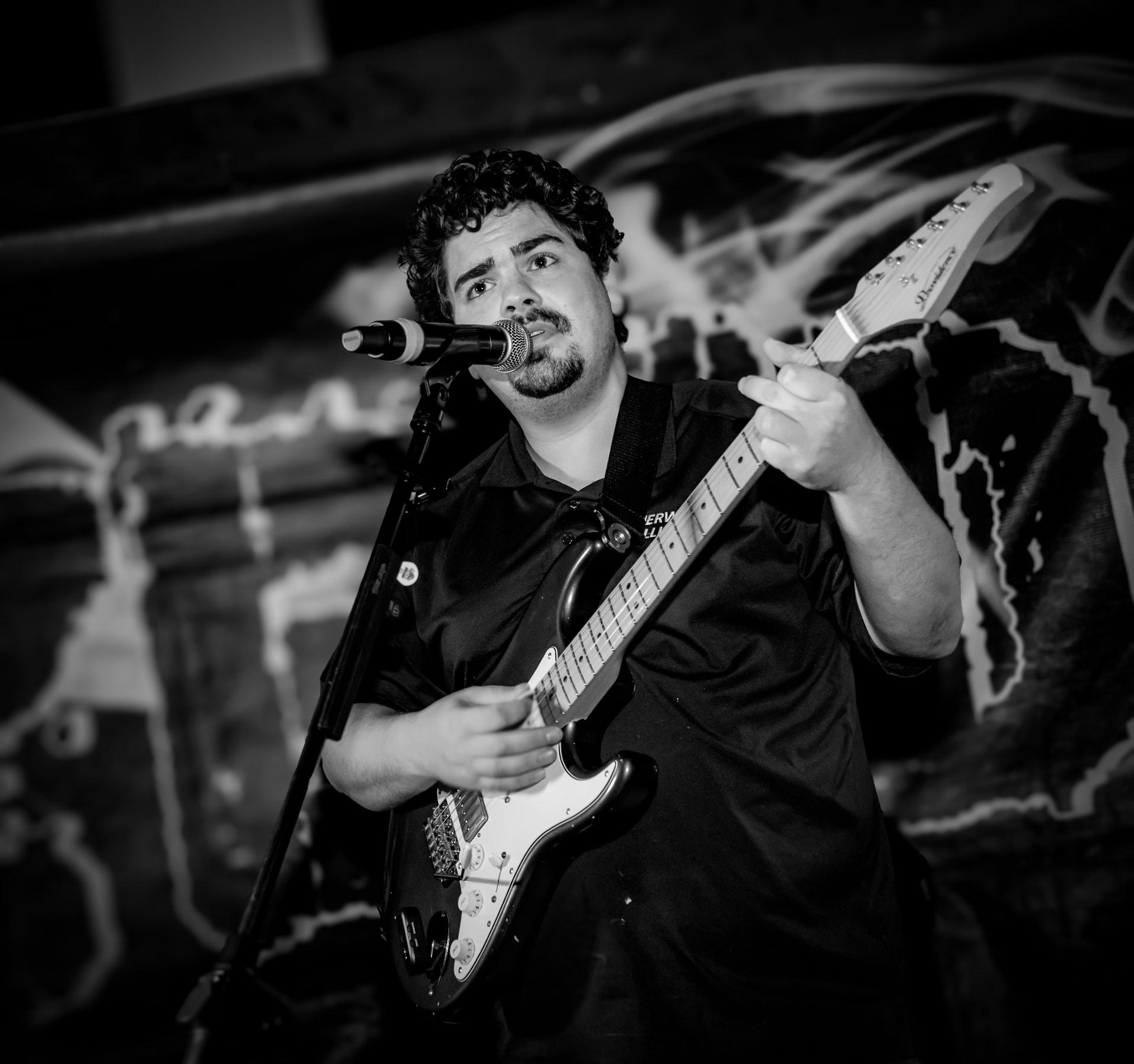 Black and white photo of Jake Frezza performing live with guitar and microphone